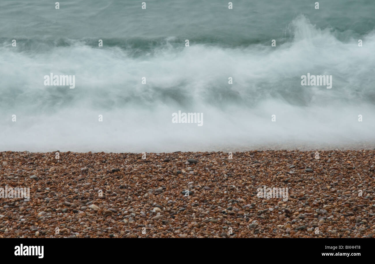 Une vague se briser sur la plage de galets pris avec une vitesse d'obturation lente. Banque D'Images