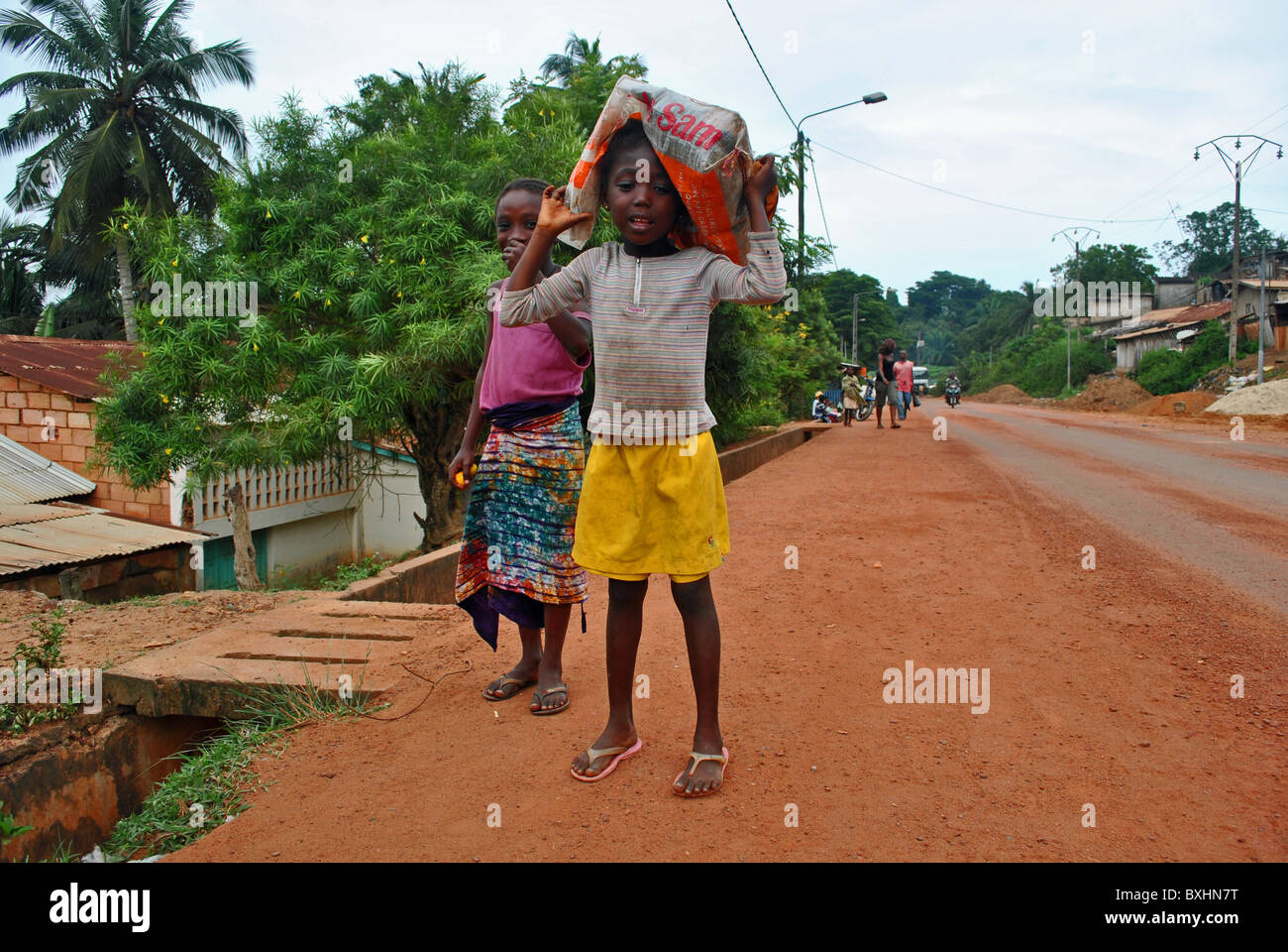 Jeune fille transportant une charge lourde à Sassandra, Côte d'Ivoire, Afrique de l'Ouest Banque D'Images