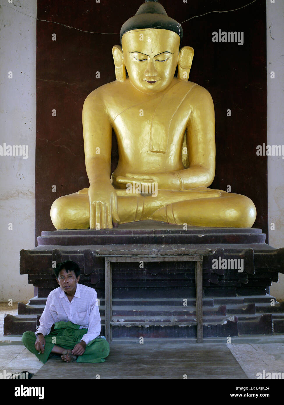 Homme assis en face d'une statue de Bouddha dans un temple dans la ville antique de Bagan, Birmanie, Myamar Banque D'Images