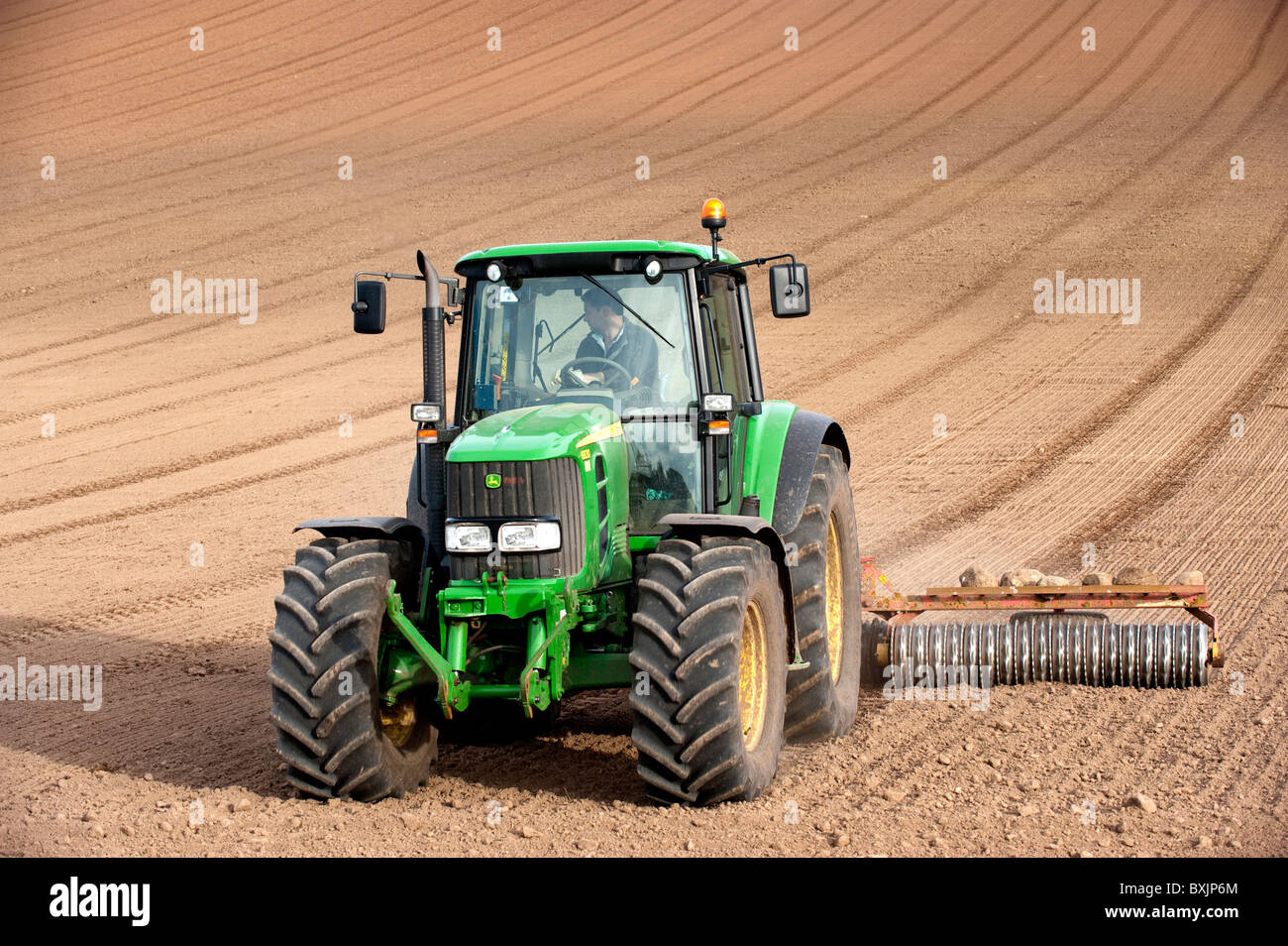 Appuyez sur le sol avec l'agriculteur, à l'aide de semence Matériel roulant tracteur John Deere. Kelso, Ecosse Banque D'Images