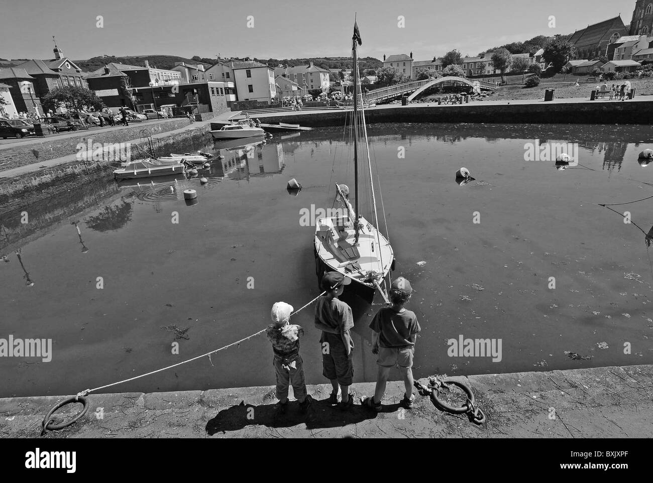 Une photo en noir et blanc de trois garçons sur le port d''aberaeron pendant le festival des fruits de mer Banque D'Images