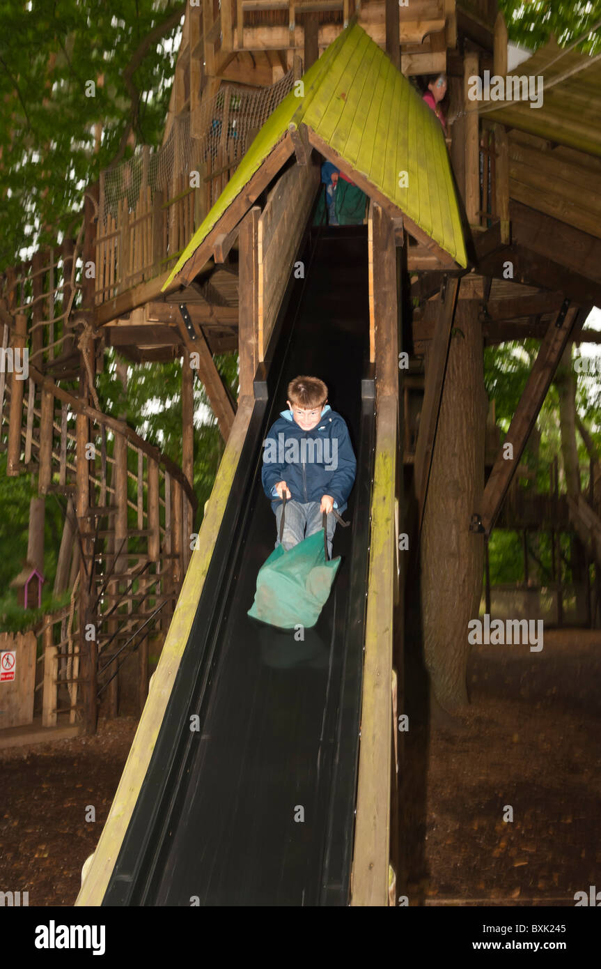 Un garçon sur une diapositive montrant le mouvement à Bewilderwood parc aventure dans Hoveton , Norfolk , Bretagne , France Banque D'Images