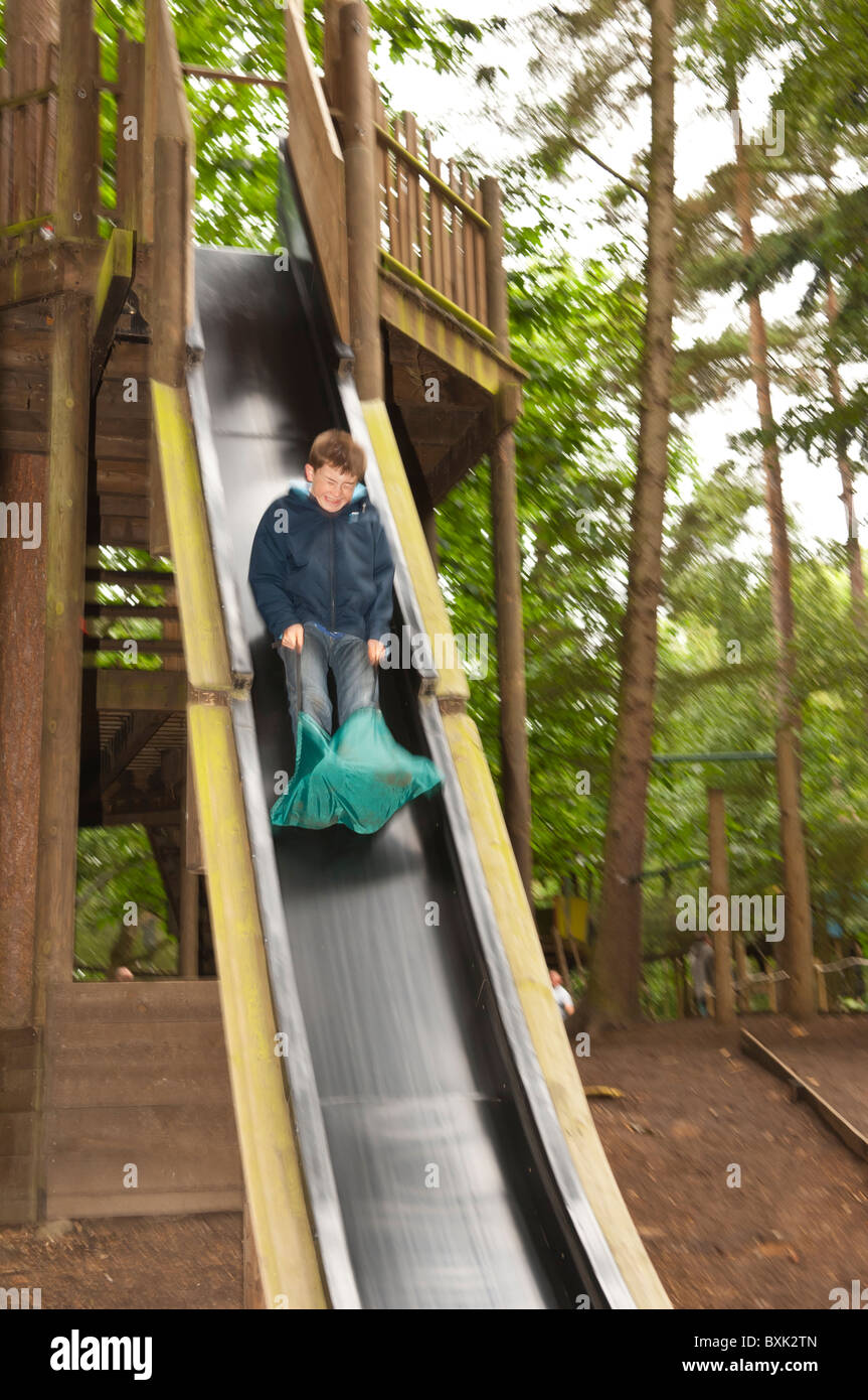 Un garçon sur une diapositive montrant le mouvement à Bewilderwood parc aventure dans Hoveton , Norfolk , Bretagne , France Banque D'Images