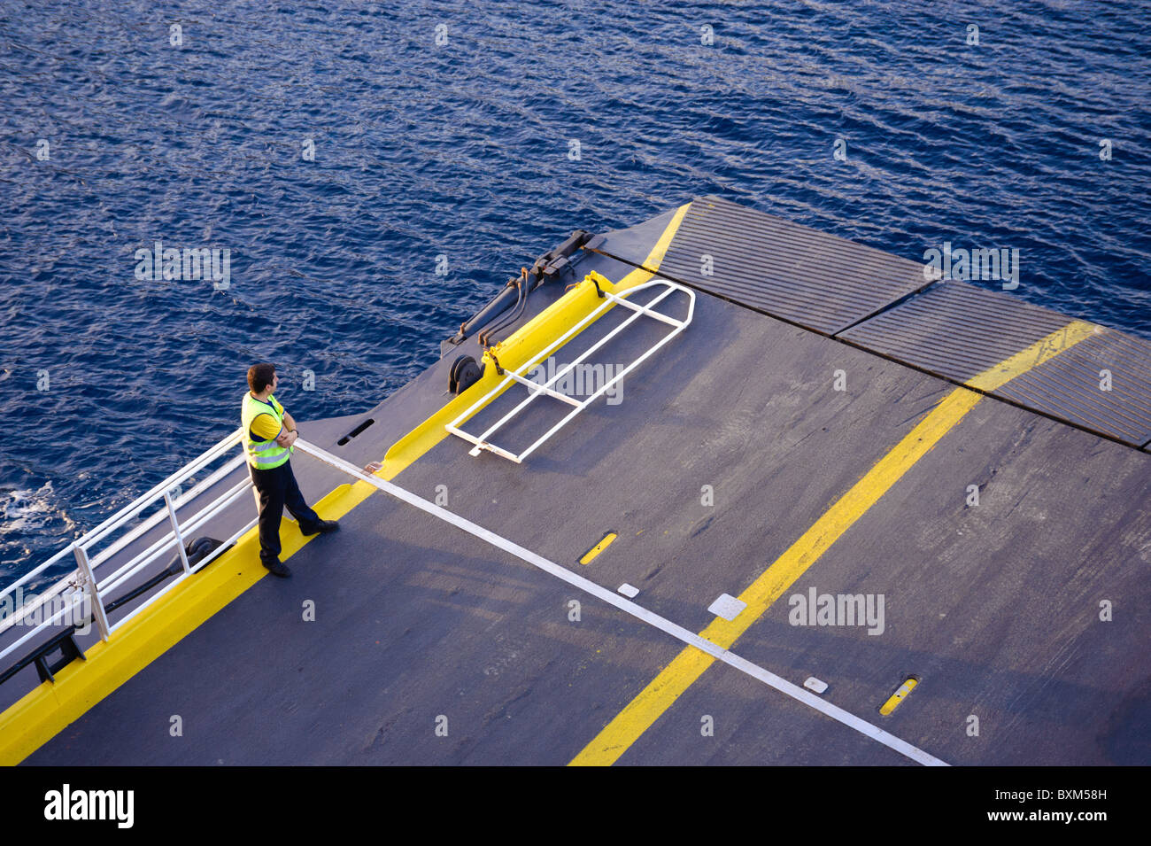 Un membre d'équipage se tient sur la rampe d'embarquement d'un ferry grec à mesure que le navire s'approche du port d'une île Ionienne. Banque D'Images
