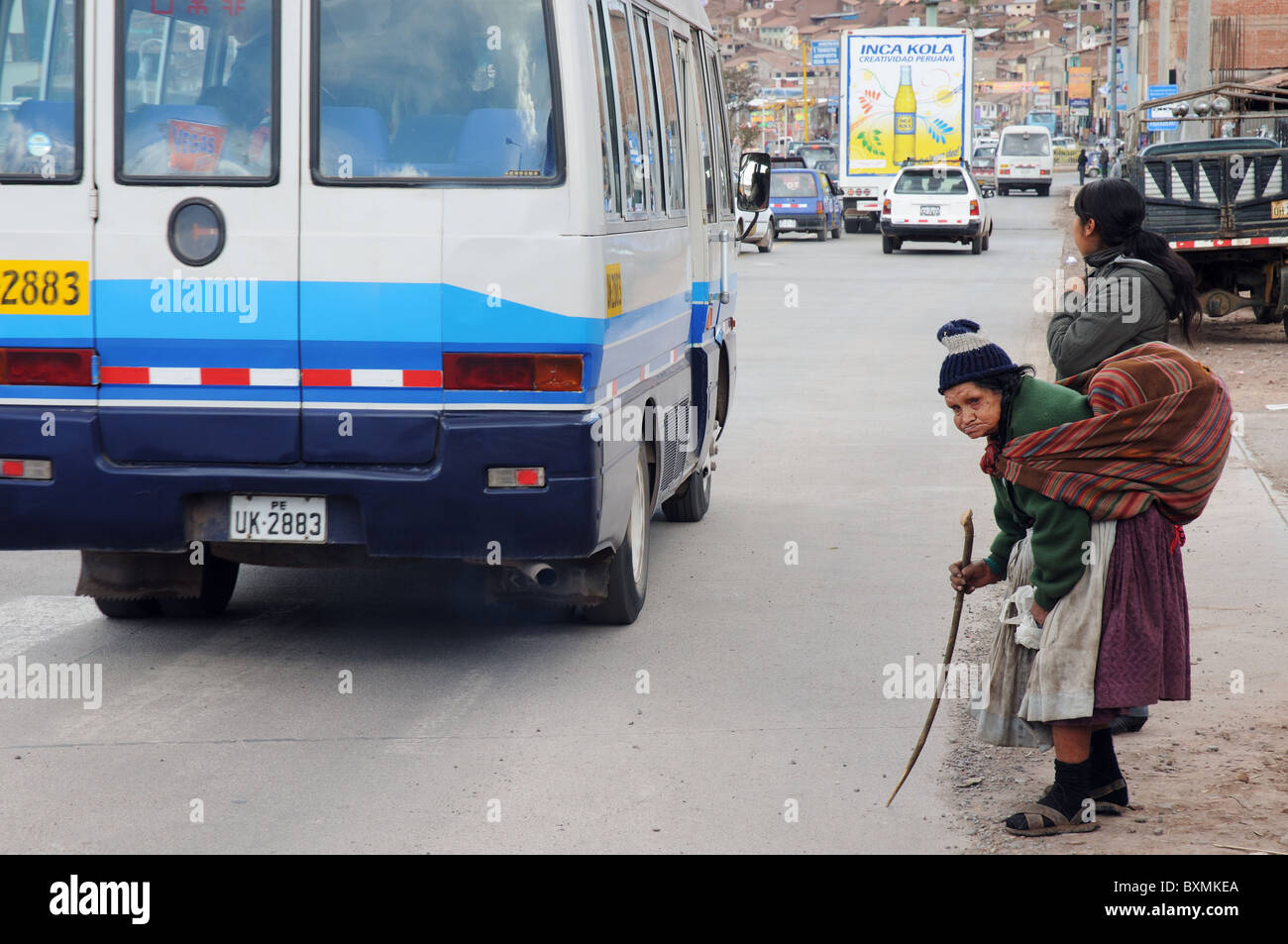 Une vieille femme courbée en attente de traverser une route très fréquentée à Cusco, Pérou Banque D'Images Une vieille femme courbée en attente de traverser une route très fréquentée à Cusco, Pérou Banque D'Images