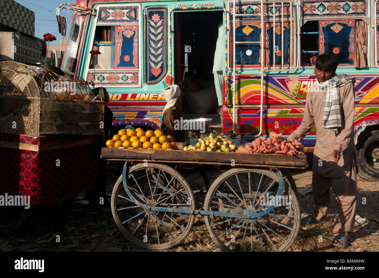 Le Pakistan après les inondations. Garçon vend des fruits à partir d'un panier à la station de bus Banque D'Images
