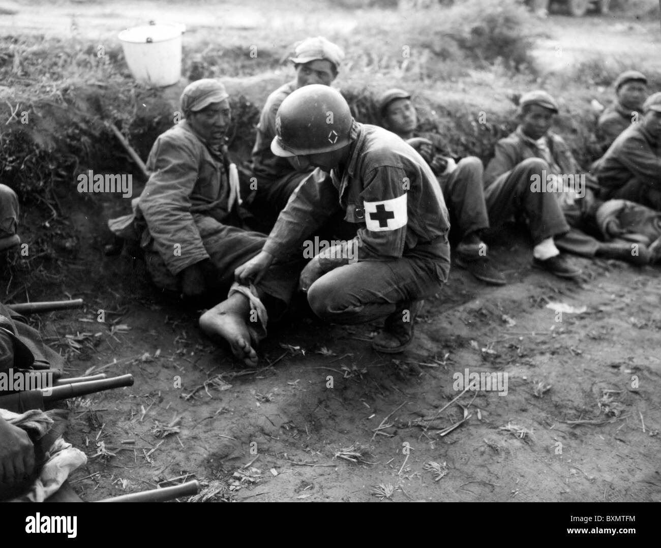 À la recherche sur les blessés Sgt Harold B. Vaughn 24e 24e bn med united states infantry examine les pieds enflés d'un chinois Banque D'Images