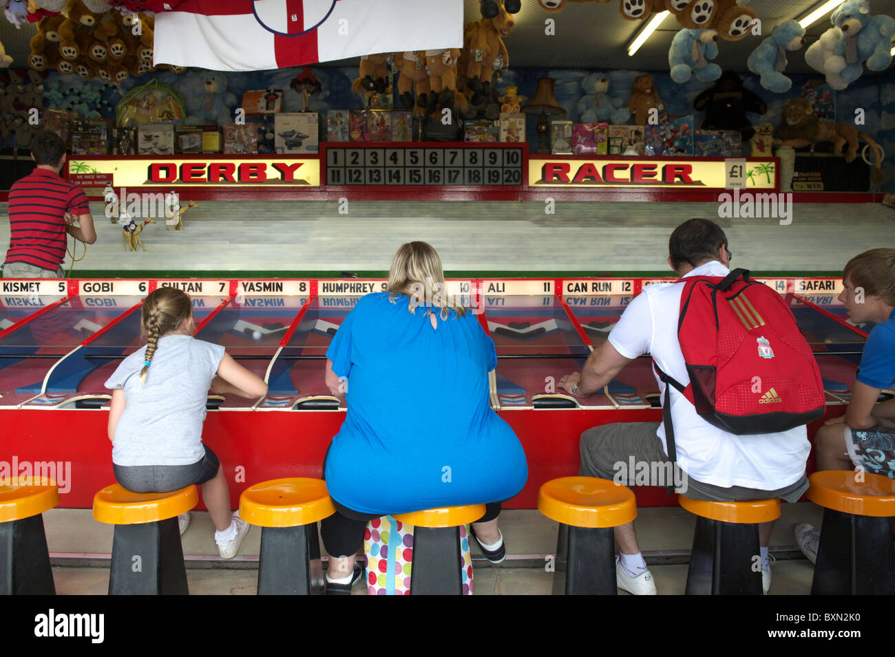 Une famille jouer Derby Racer sur un stand de jeux sur un quai à Great Yarmouth en été Banque D'Images