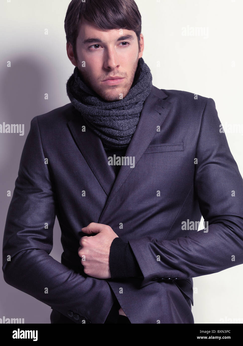 Fashion portrait d'un jeune homme vêtu d'un blazer noir et un foulard isolé sur fond blanc Banque D'Images
