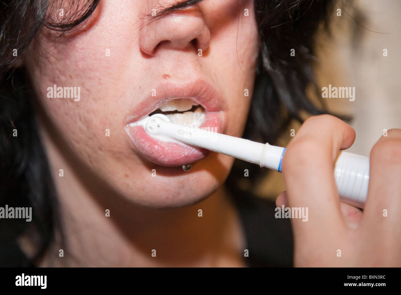 Adolescent avec piercing se brosser les dents avec une brosse à dents  électrique Photo Stock - Alamy