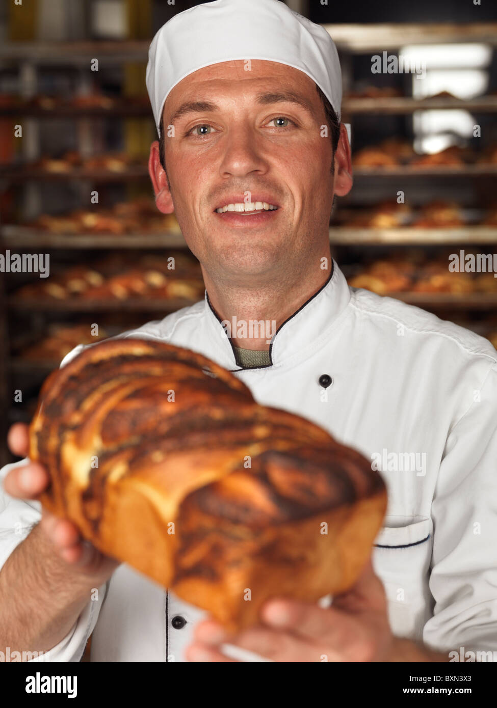 Smiling Baker un pain fraîchement cuit de pain dans ses mains Banque D'Images