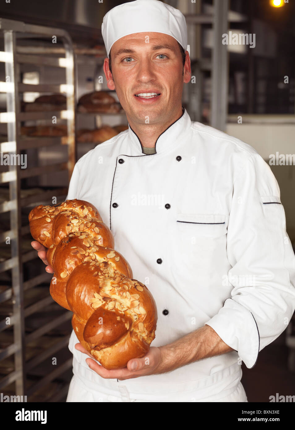 Smiling Baker un pain fraîchement cuit de pain challah dans ses mains Banque D'Images