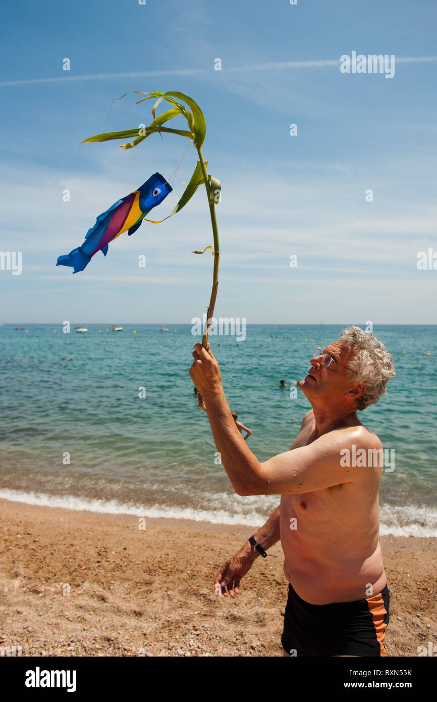 Un homme âgé est de jouer avec les poissons du vent à la plage Banque D'Images