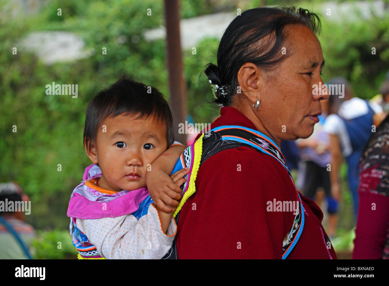 Yi femme de minorité ethnique avec enfant sur le marché, Yuanyang, province du Yunnan, Chine Banque D'Images