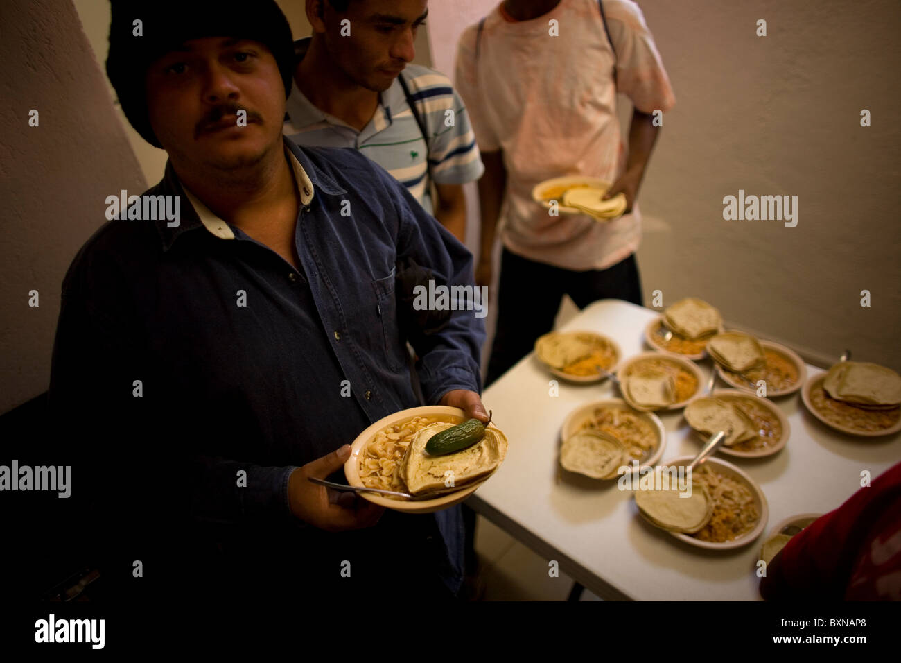 Un migrant d'Amérique centrale traversant le Mexique à travailler aux États-Unis faire une ligne pour l'alimentation dans un refuge dans la ville de Mexico Banque D'Images