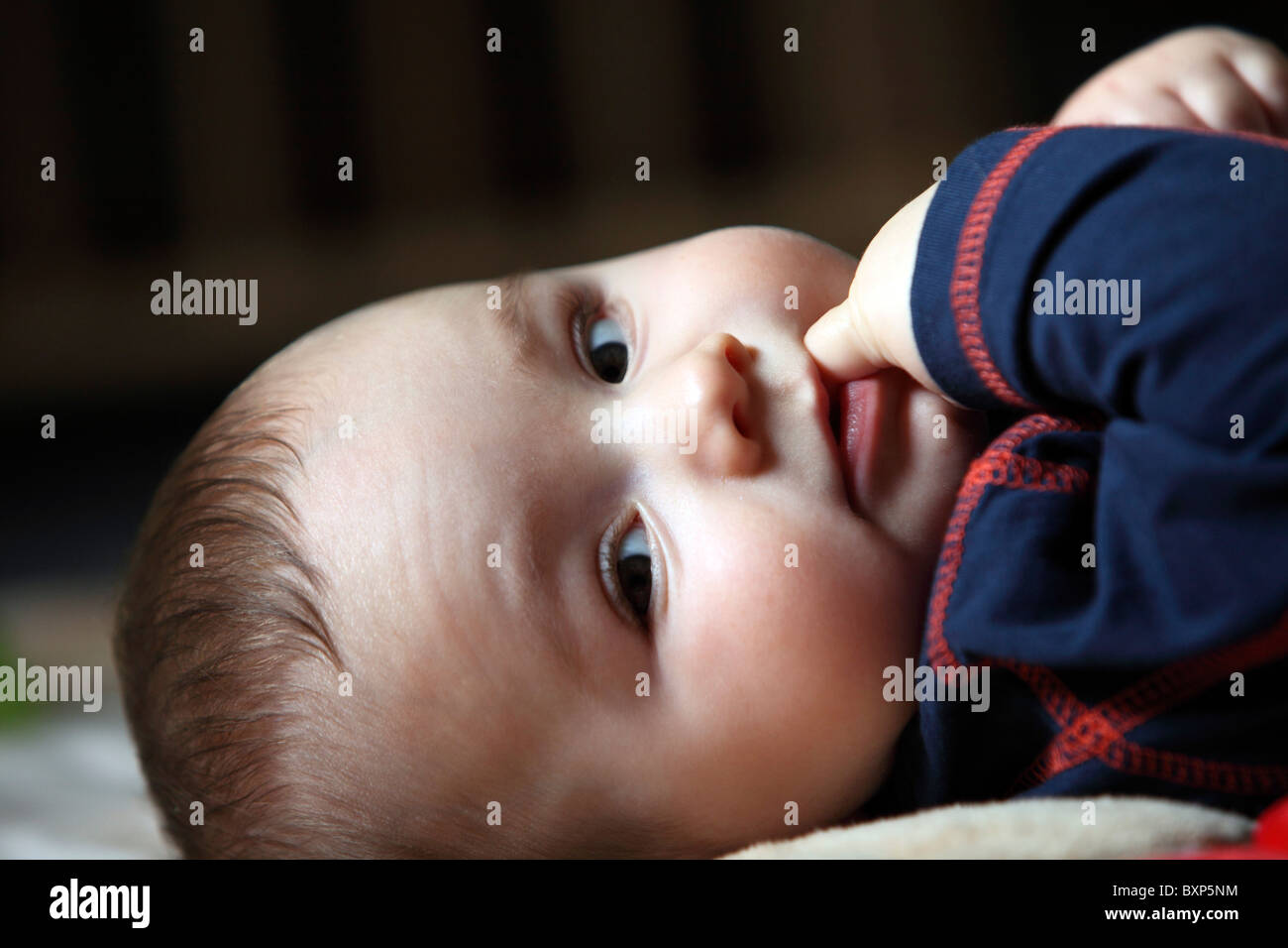 6 mois du petit garçon portant ses enfants en chambre, sur une couverture, souriant, heureux et à l'environnement. Banque D'Images