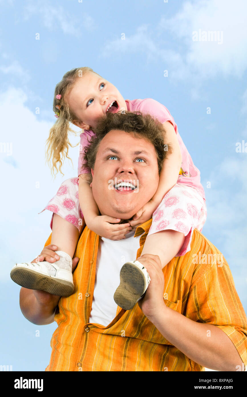 Portrait de fille assis sur les épaules de son papa sur le fond de ciel Banque D'Images