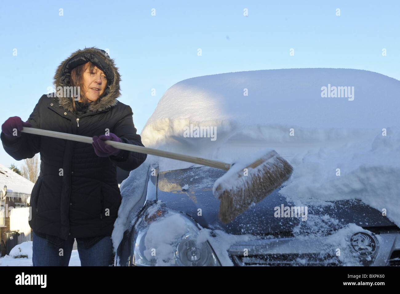 Une femmes efface la neige de sa voiture. Banque D'Images