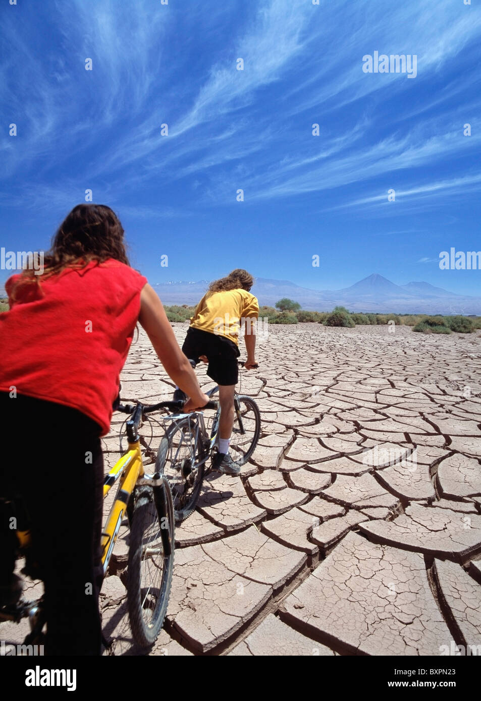 Deux cyclistes roulant sur la boue fissuré dans le désert d'Atacama Banque D'Images