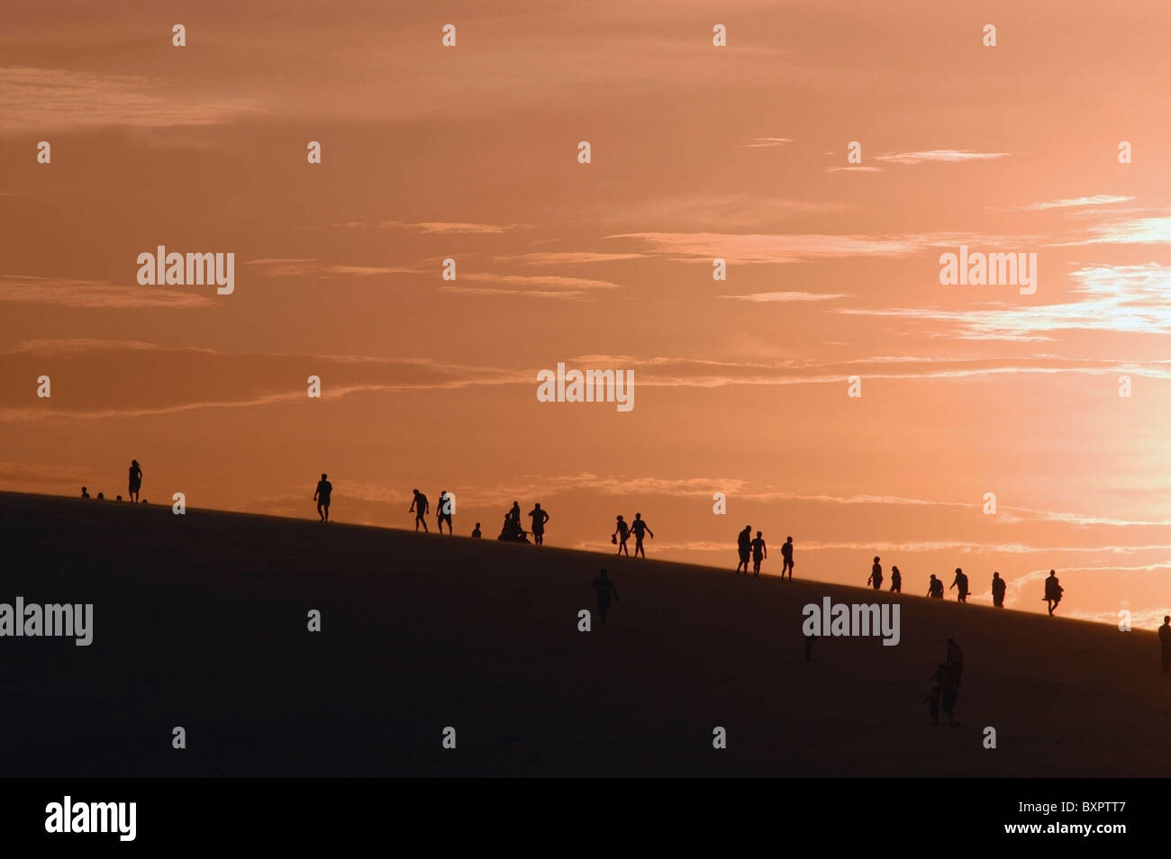 Les gens en silhouette Escalade de dunes de sable Banque D'Images