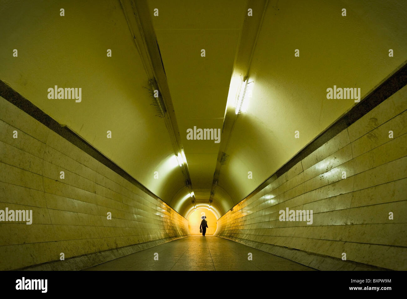 Femme avec un sac sur la tête de marcher à travers un tunnel pour piétons Banque D'Images