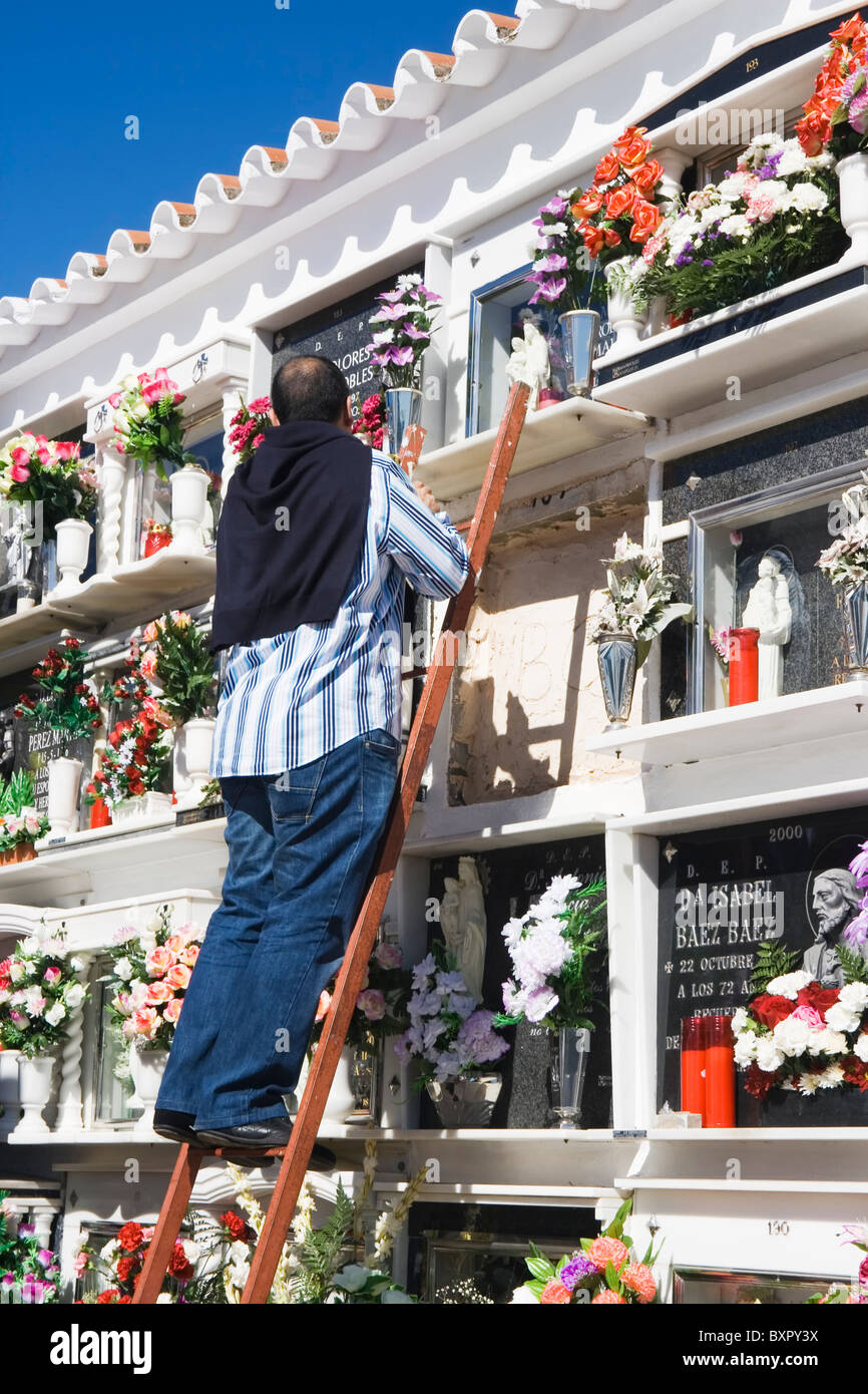 Laissant l'homme fleurs et nettoyage des niches de ses proches sur la Toussaint au cimetière local. Banque D'Images