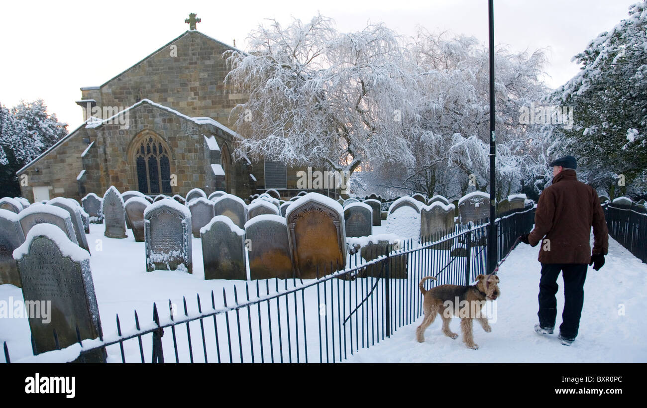 L'homme et le chien marcher par saint Pierre et Saint Paul dans la neige du shérif devient Yorkshire Angleterre Royaume-Uni Banque D'Images