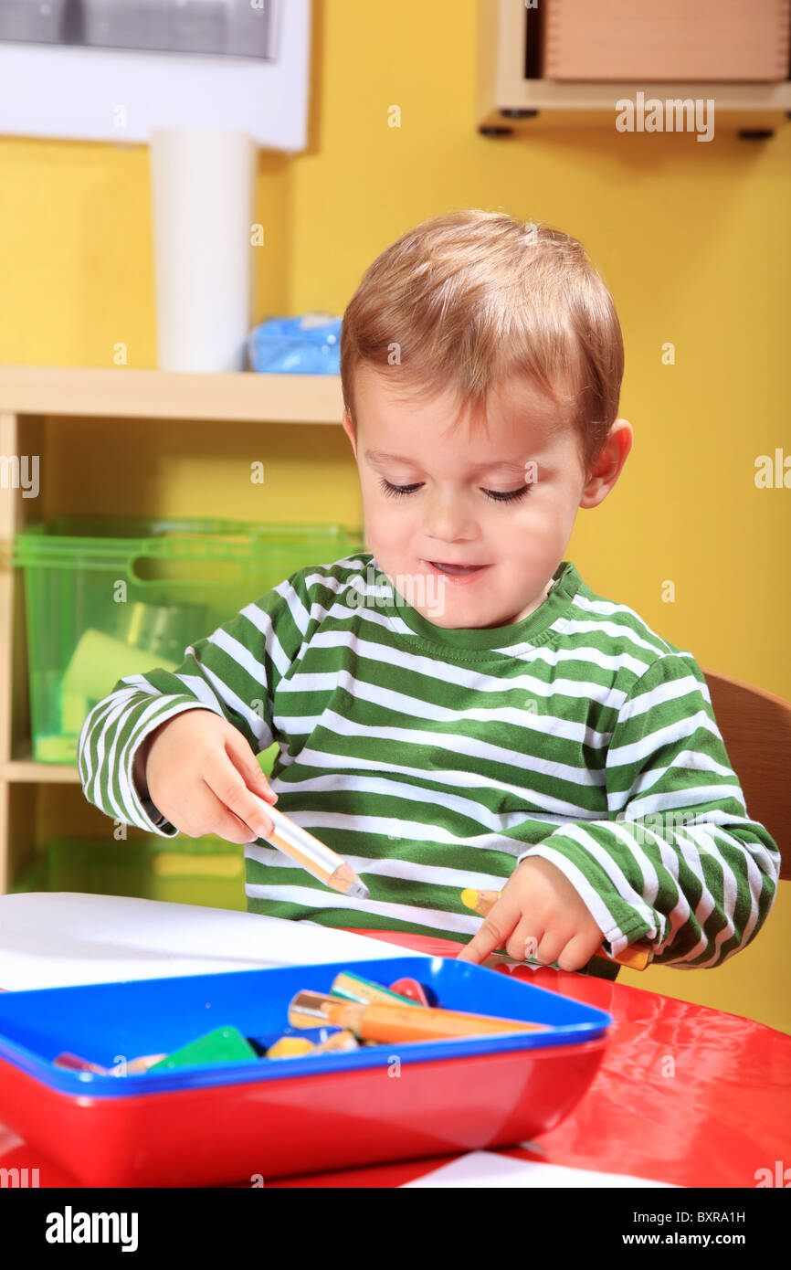 Cute caucasian toddler dessiner une image en maternelle. Banque D'Images