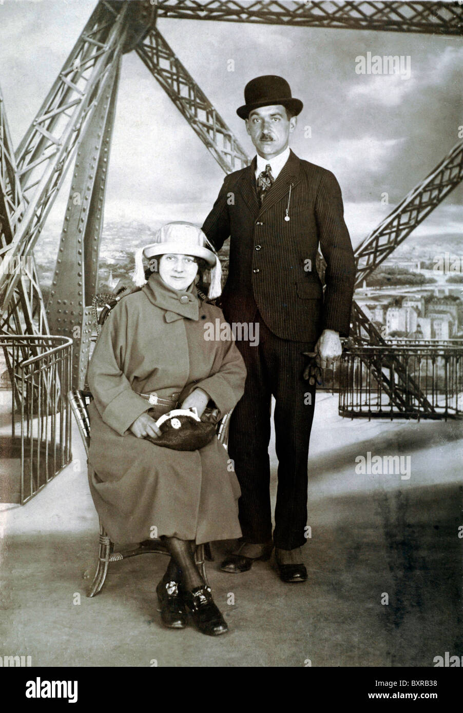 Touristes ou couple de touristes photographiés sur ou avec la Tour Eiffel comme fond peint ou Studio Prop, Paris (c1920-30s)^France. Studio photo souvenir formel Banque D'Images