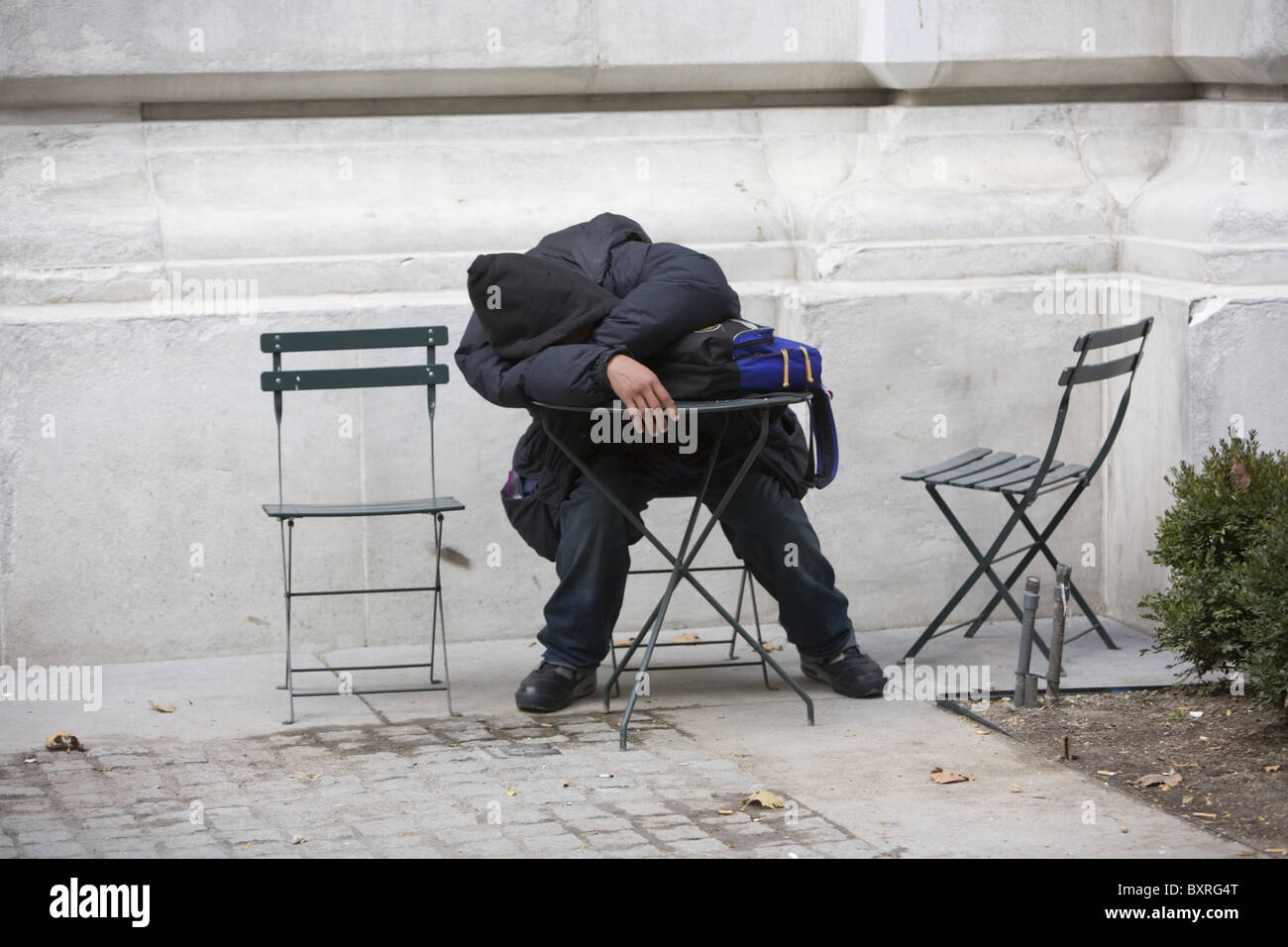 Homme fatigué pan à une table dans le froid par la Bibliothèque publique de New York à Manhattan. Banque D'Images