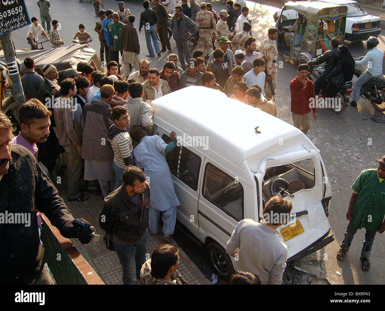 Les gens recherchent un véhicule endommagé qui a été détruit dans un accident après l'accident de la route à Rizvia Chowrangi à Karachi le lundi, Banque D'Images