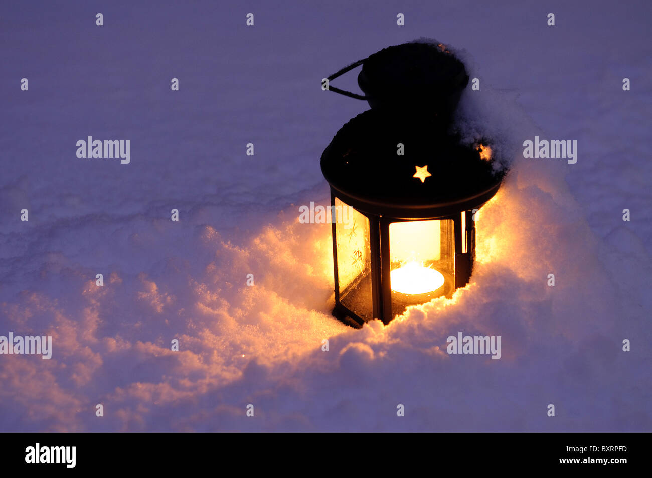Vieille lanterne avec une bougie sur la neige la nuit Banque D'Images