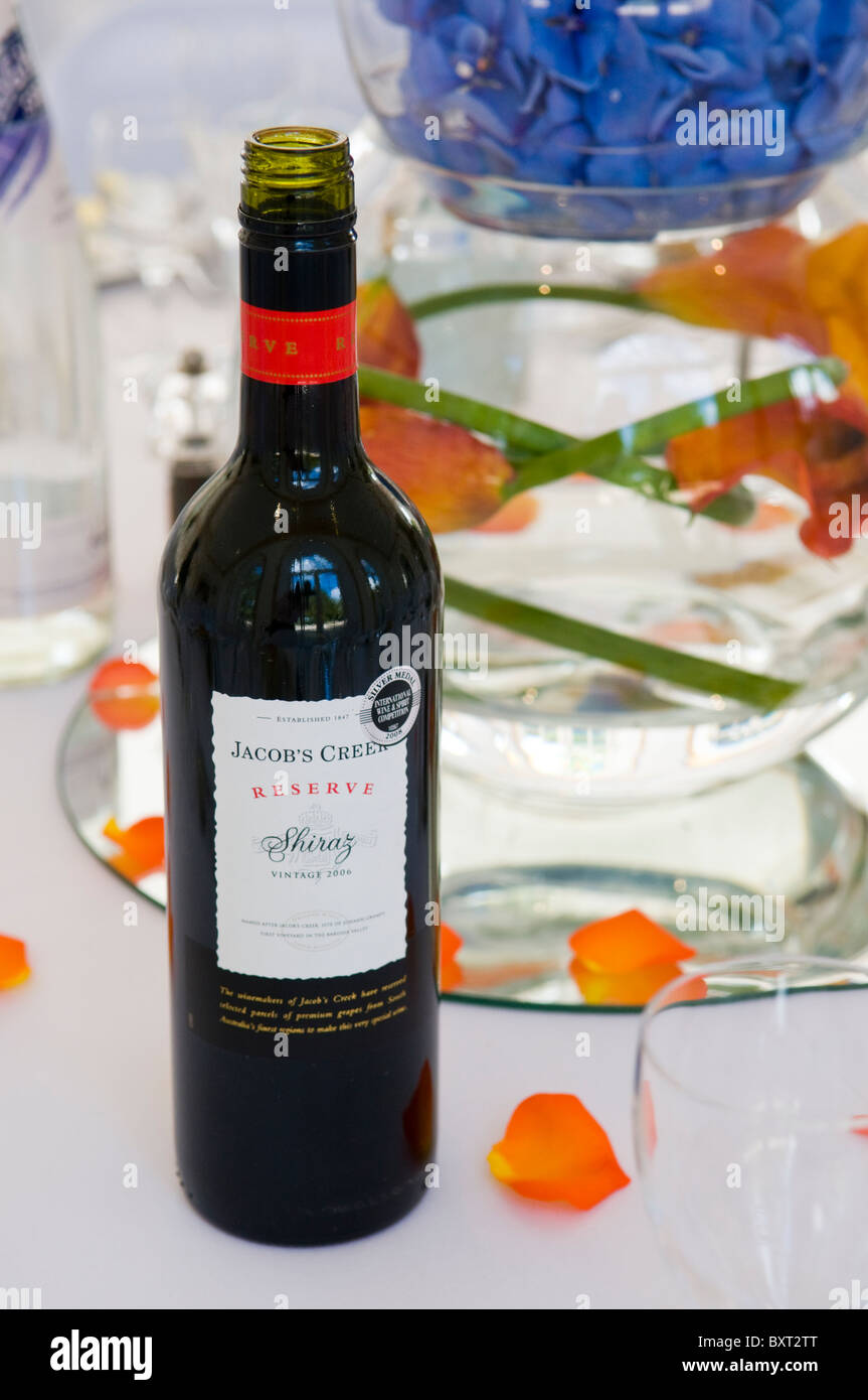 Une bouteille de Jacob's Creek Shiraz réserve sur une table avec des bols de pétales de fleurs orange et bleu Banque D'Images