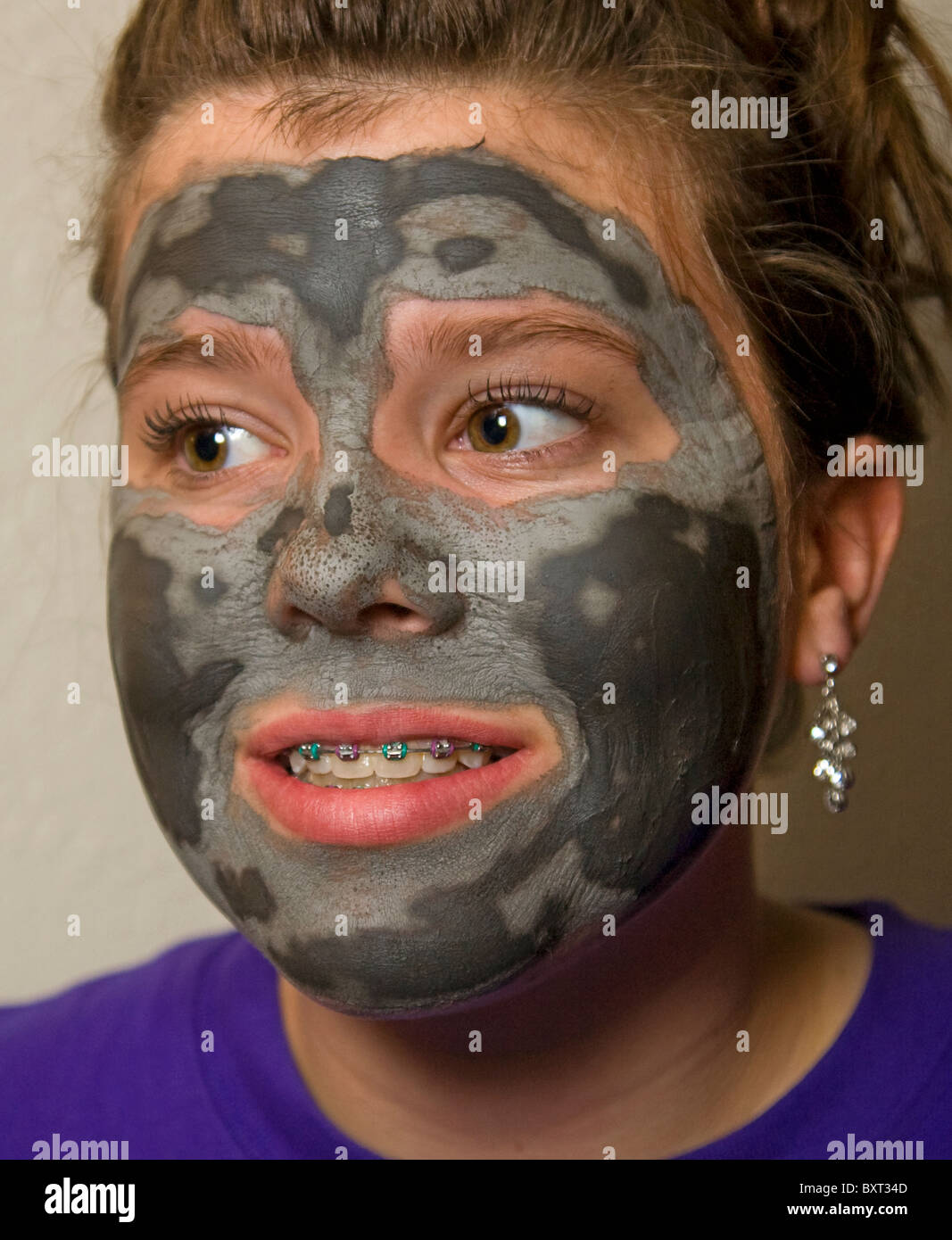 Une jeune fille portant des accolades sur ses dents et un masque de beauté du visage se prépare à une date Banque D'Images