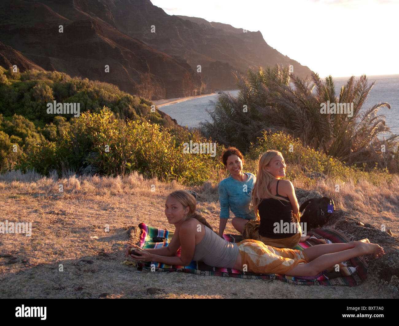 Trois belle femme au-dessus de Kalalau beach le Heiau temple près de coucher du soleil, la côte Napali, Kauai, Hawaii Banque D'Images