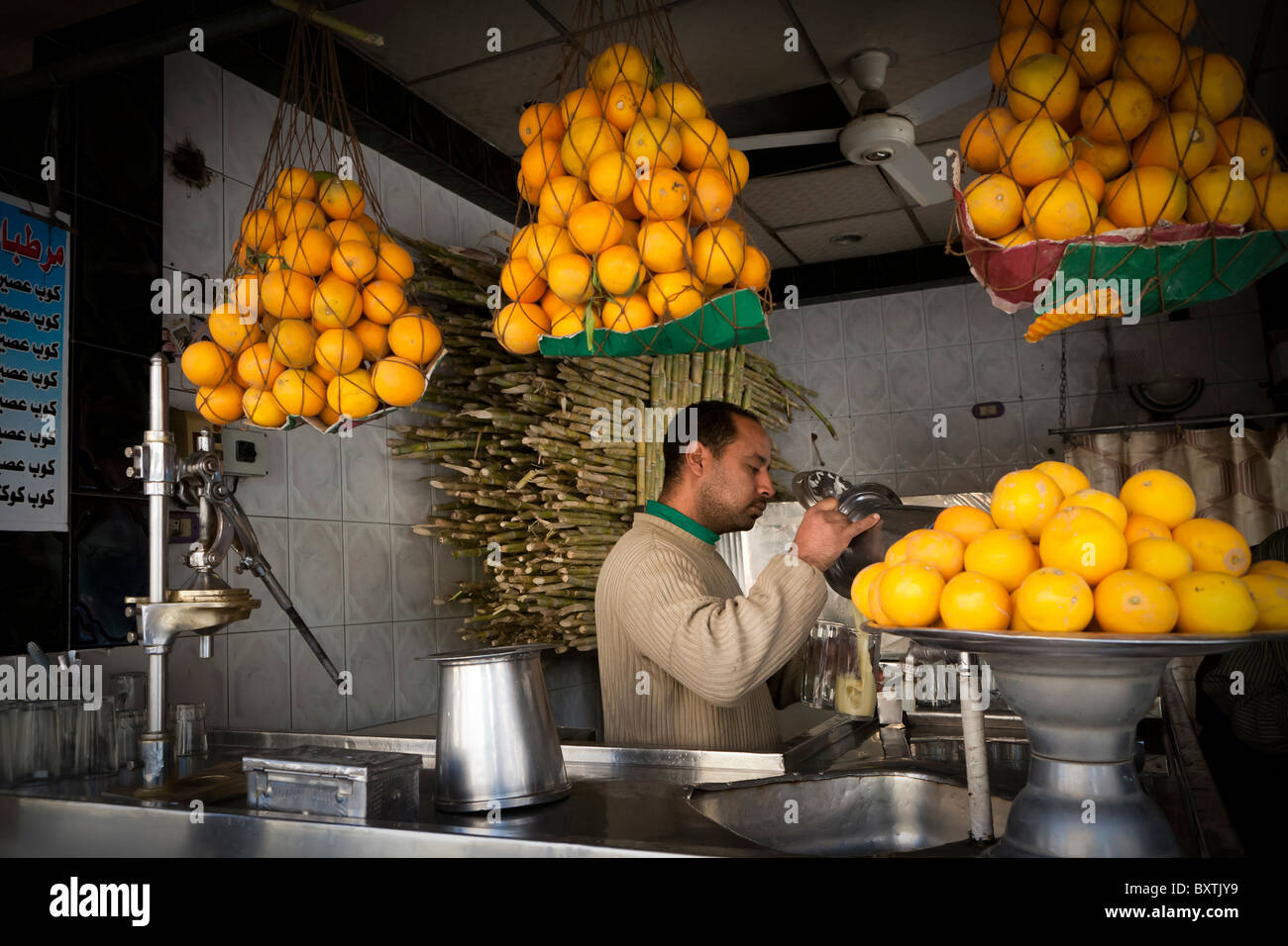 L'homme travaillant à un jus de fruit et le sucre peut faire un jus dans un magasin de la rue du marché, Luxor, Egypte, Afrique du Sud Banque D'Images