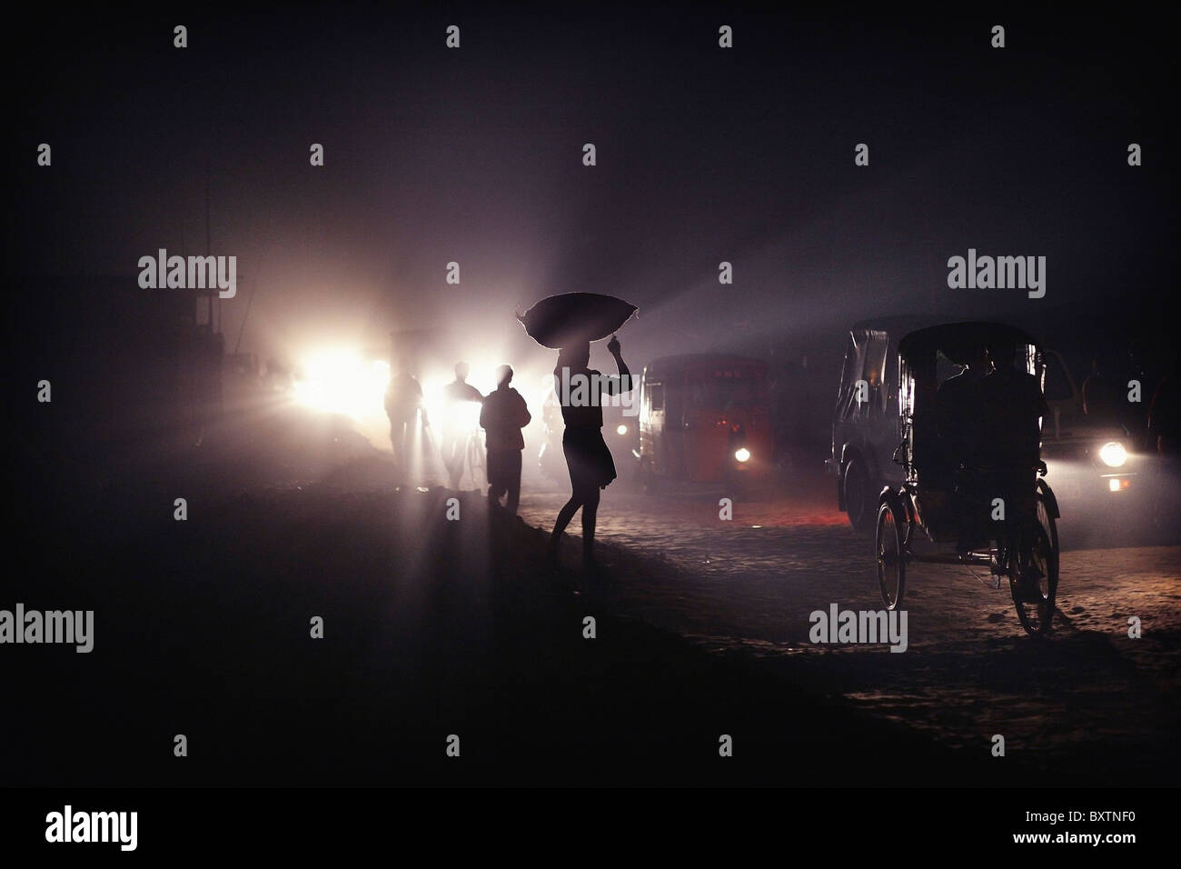 Silhouettes de trafic et les gens portent des sacs sur leurs têtes la nuit Banque D'Images