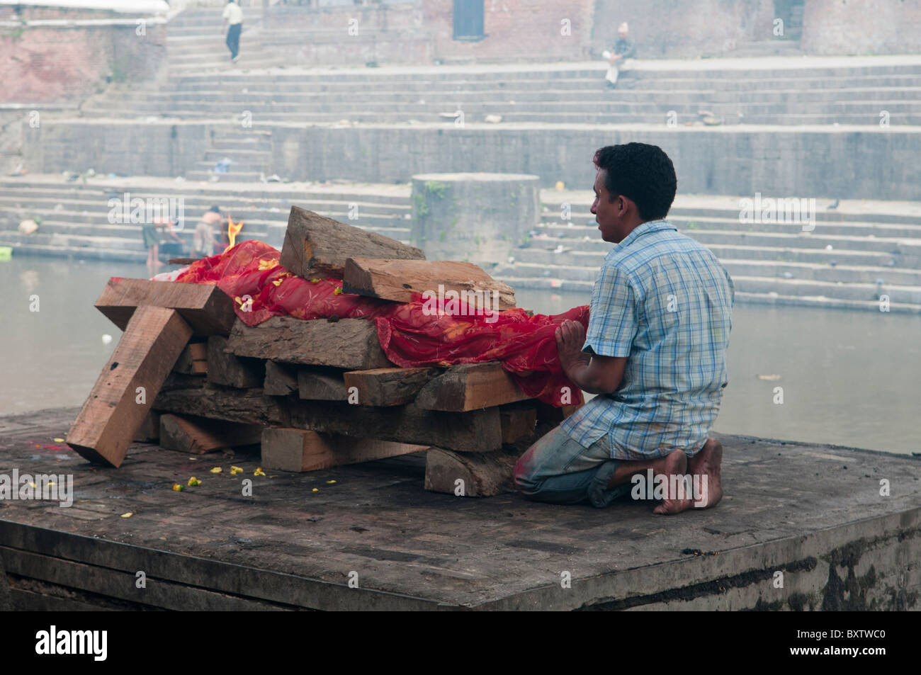 Un fils dit au revoir à un salon funéraire crémation sur la rivière Bagmati au Temple d'Pahsupatinath à Katmandou, Népal Banque D'Images