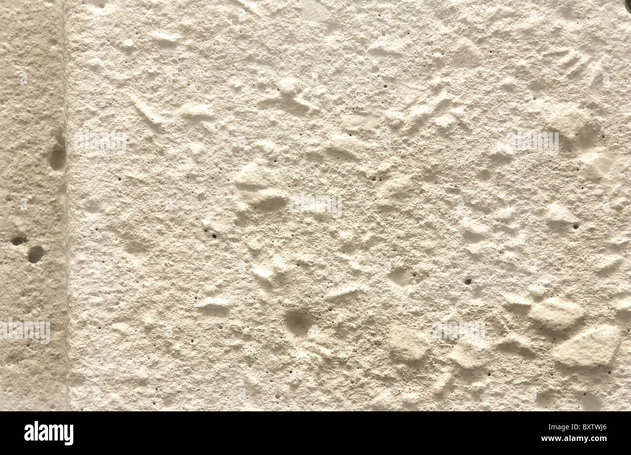 La texture de fond d'un mur de ciment avec petits trous et projeter des pierres intégré d'ombres. Banque D'Images