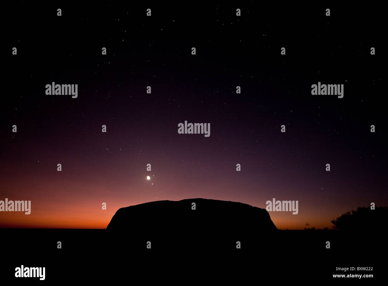 L'Australie, Territoire du Nord, Uluru - Kata Tjuta National Park, Dawn silhouettes Ayers Rock sur matin d'été dans l'arrière-pays Banque D'Images