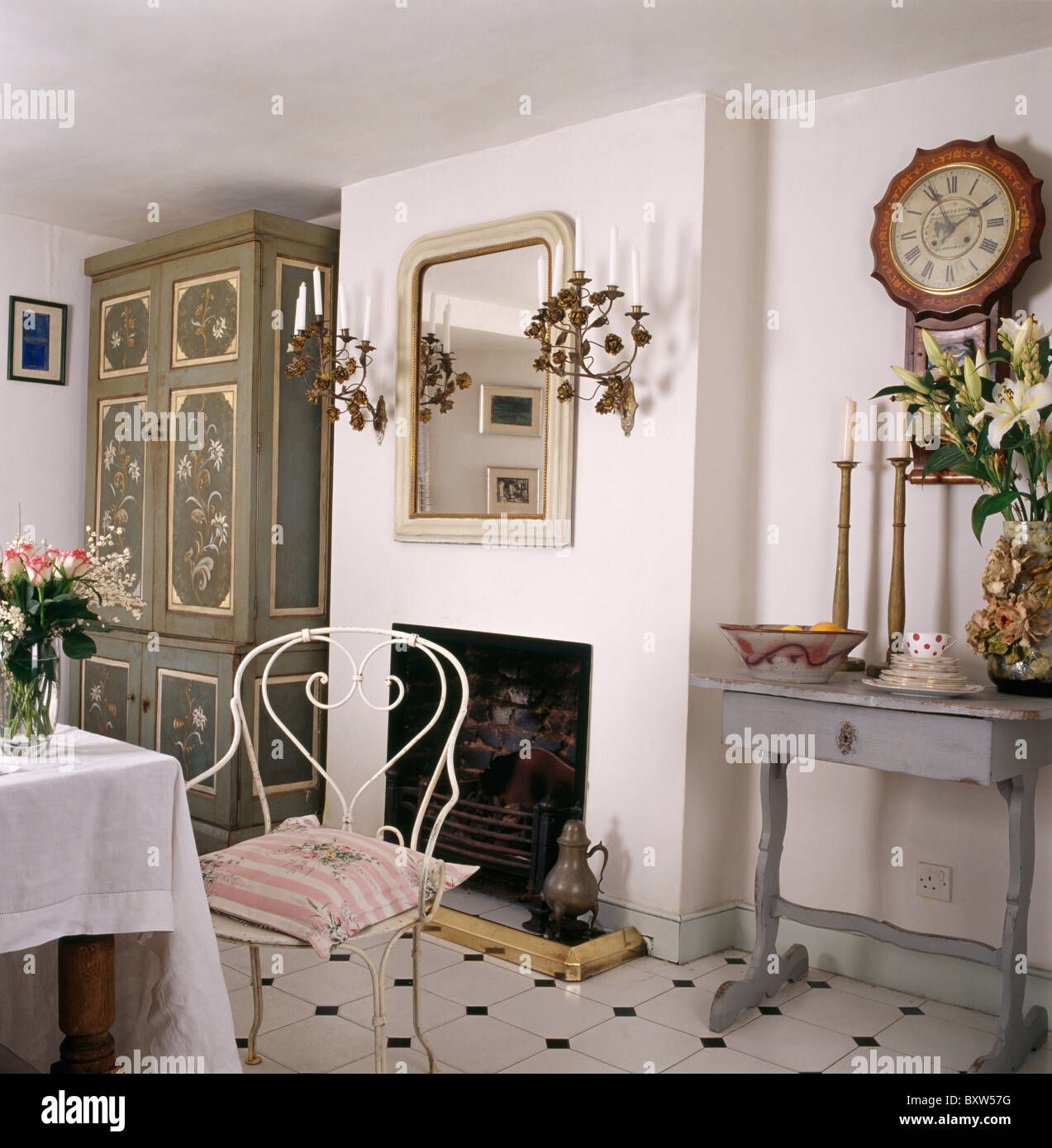Armoire peinte en coin de salle à manger avec chaise en métal blanc à table et horloge ancienne console tableau peint en gris ci-dessus Banque D'Images
