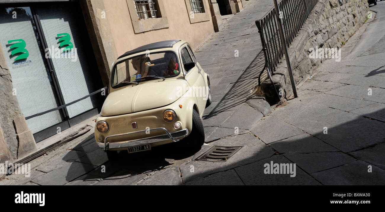 Une petite voiture rétro fiat 500 en tournant dans la rue à Cortona, Toscane, Italie Banque D'Images