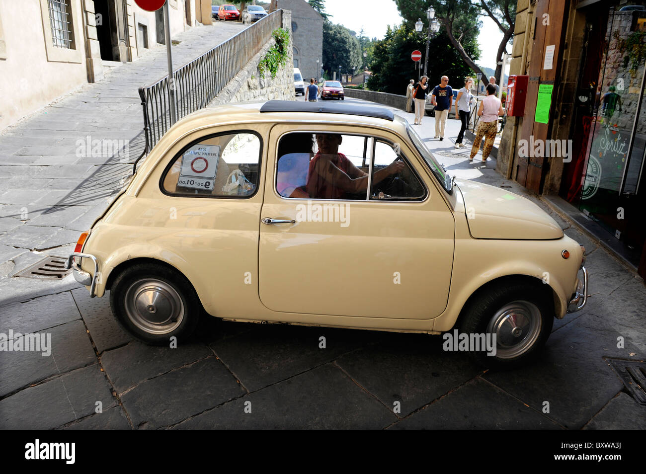 Une petite voiture rétro fiat 500 en tournant dans la rue à Cortona, Toscane, Italie Banque D'Images