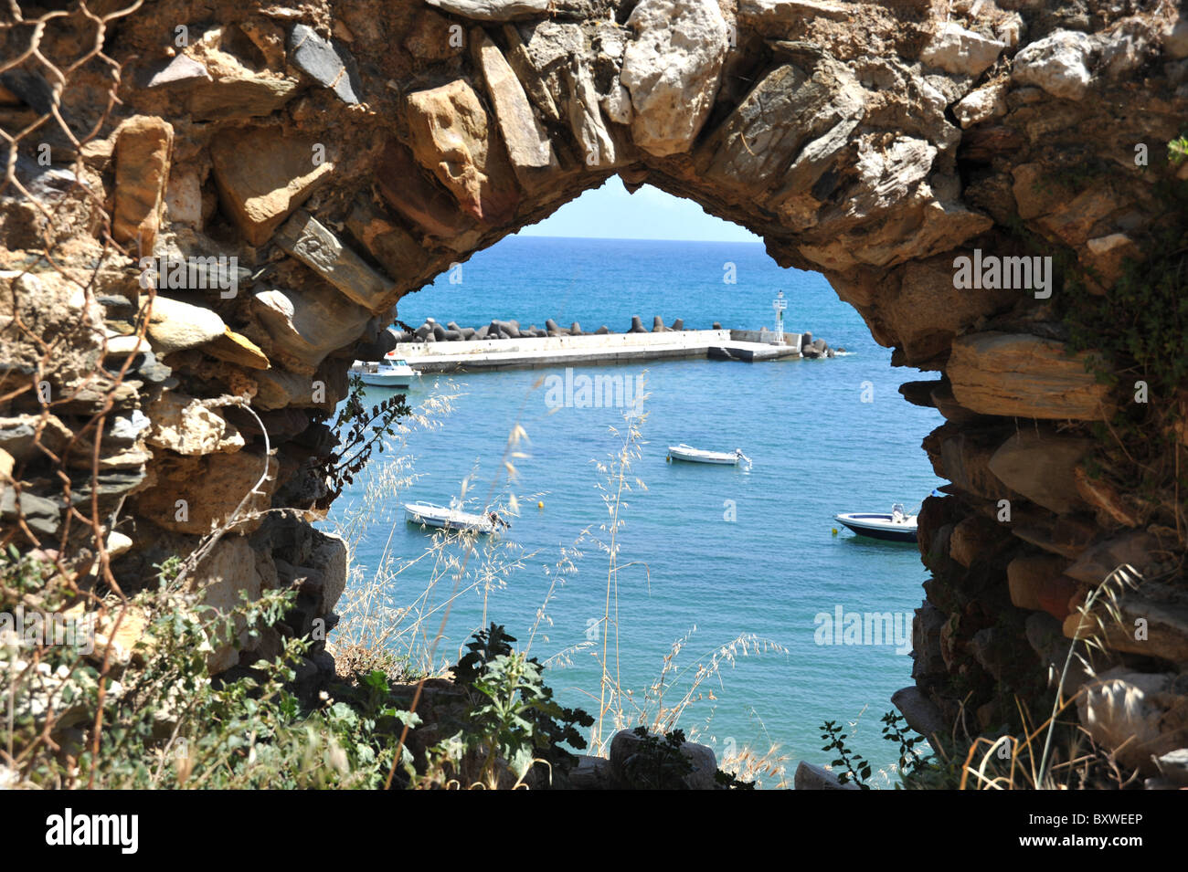 Vue sur le port à Panormo, vu à travers une arche des ruines du château. Crète, Grèce Banque D'Images