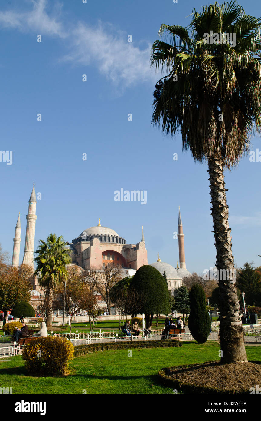 Hagia Sophia dômes et minarets Istanbul Turquie // ISTANBUL, Turquie — la basilique Sainte-Sophie vue depuis le parc du Sultan Ahmet, montrant ses dômes, minarets et contreforts distinctifs contre la ligne d'horizon d'Istanbul. L'extérieur du bâtiment reflète à la fois ses origines byzantines et ses ajouts ottomans, avec le dôme central flanqué de quatre minarets ajoutés après sa conversion en mosquée en 1453. Banque D'Images