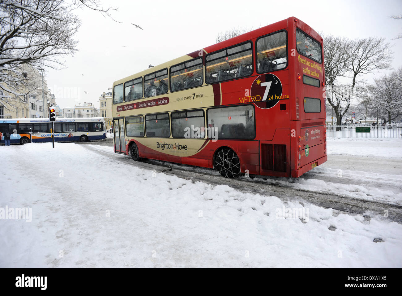 Un bus à l'aide de chaînes à neige les périphériques à Brighton après les fortes chutes de neige couvre les routes Banque D'Images