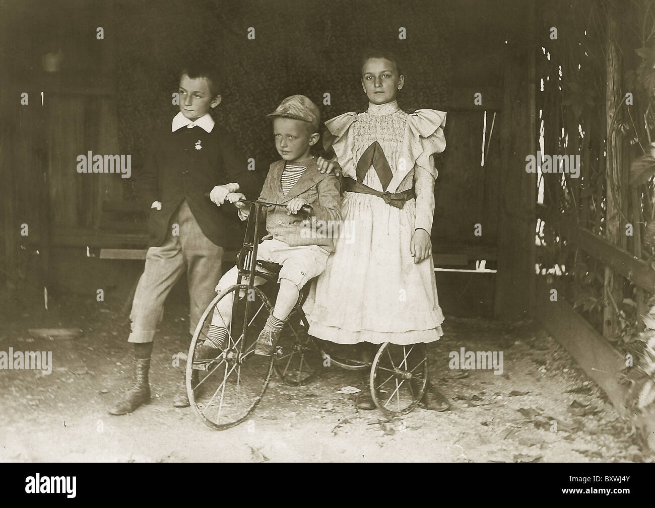 Trois frères et sœurs partagent un vélo. vers : 1900-1910 Banque D'Images