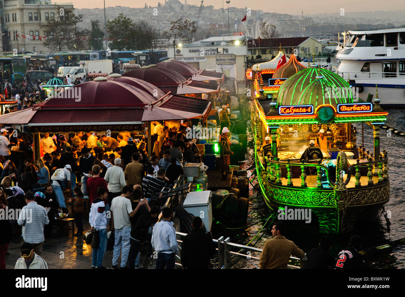 Restaurants flottants Balik Ekmek Eminonu Istanbul // ISTANBUL, Turquie — les bateaux Balik ekmek bordent le front de mer d'Eminonu le long de la Corne d'Or près du pont de Galata. Ces restaurants flottants, connus localement sous le nom de balikci tekneleri, sont amarrés le long du quai et servent des sandwichs de poisson grillé aux visiteurs et aux habitants de ce quartier populaire du front de mer. Le balik ekmek est une cuisine de rue emblématique d’Istanbul composée de maquereaux grillés servis dans du pain blanc, souvent accompagnés d’oignons et de laitue. Eminonu est une zone commerciale historique du côté européen d'Istanbul où la Corne d'Or rencontre le Banque D'Images