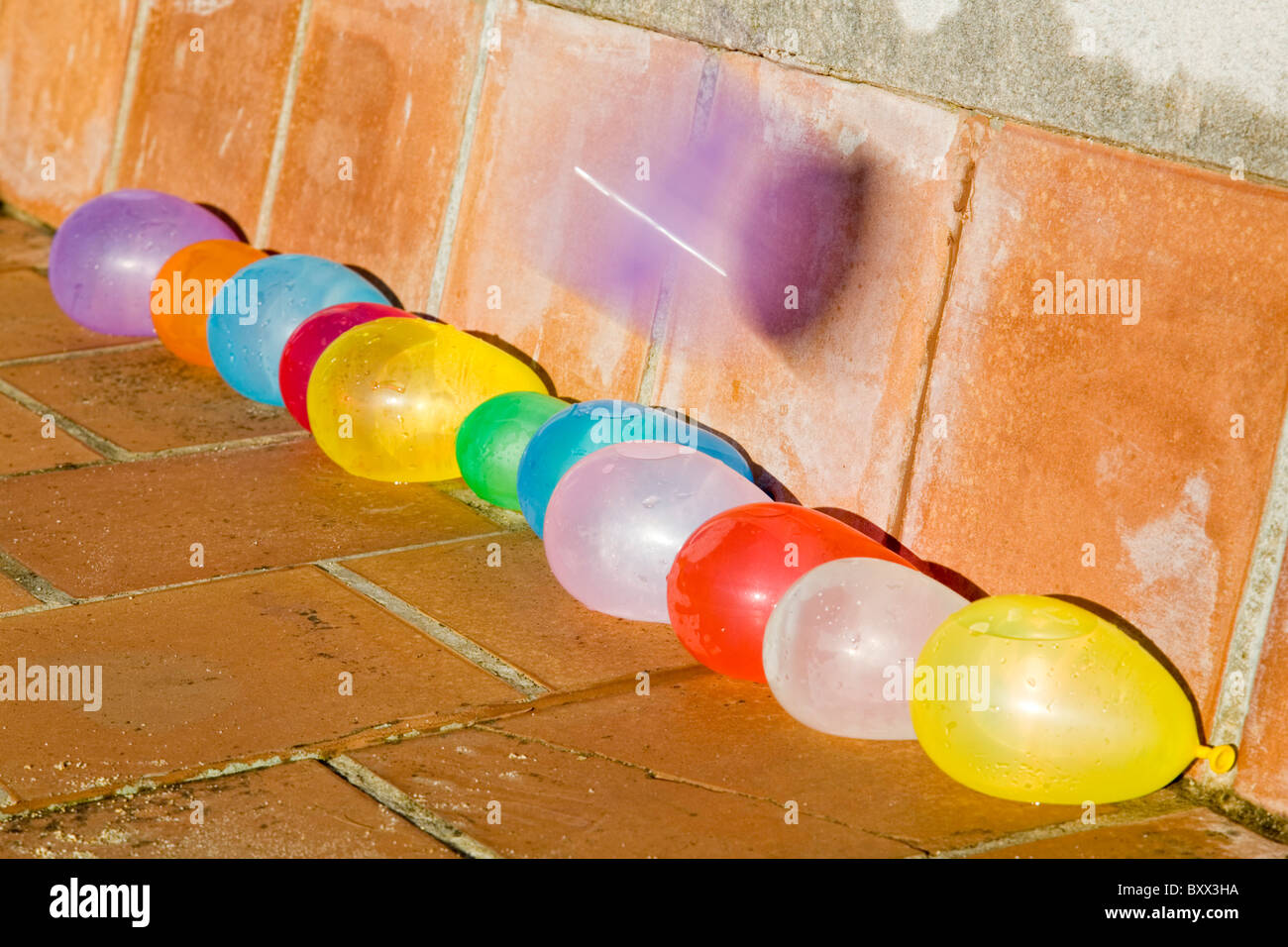 Rempli d'eau ballons multicolores dans une ligne, avec un ballon sur le point d'exploser Banque D'Images