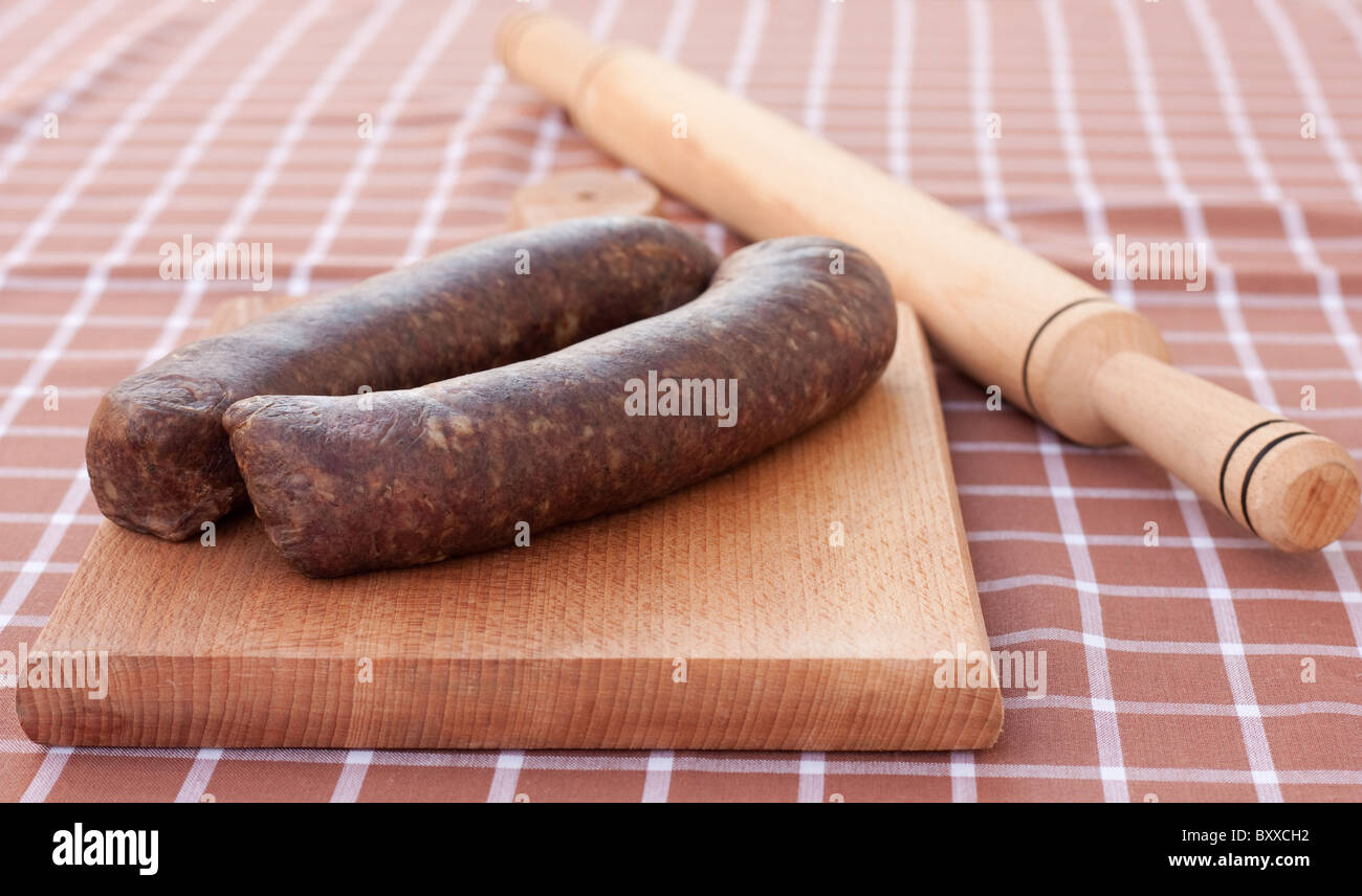 Saucisses faites maison,prêt à être roulé avec roulement-pin sur planche à découper en bois Banque D'Images